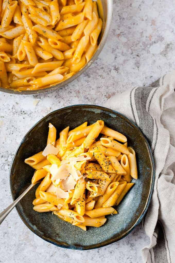 Butternut Squash pasta in a blue bowl on a white table.