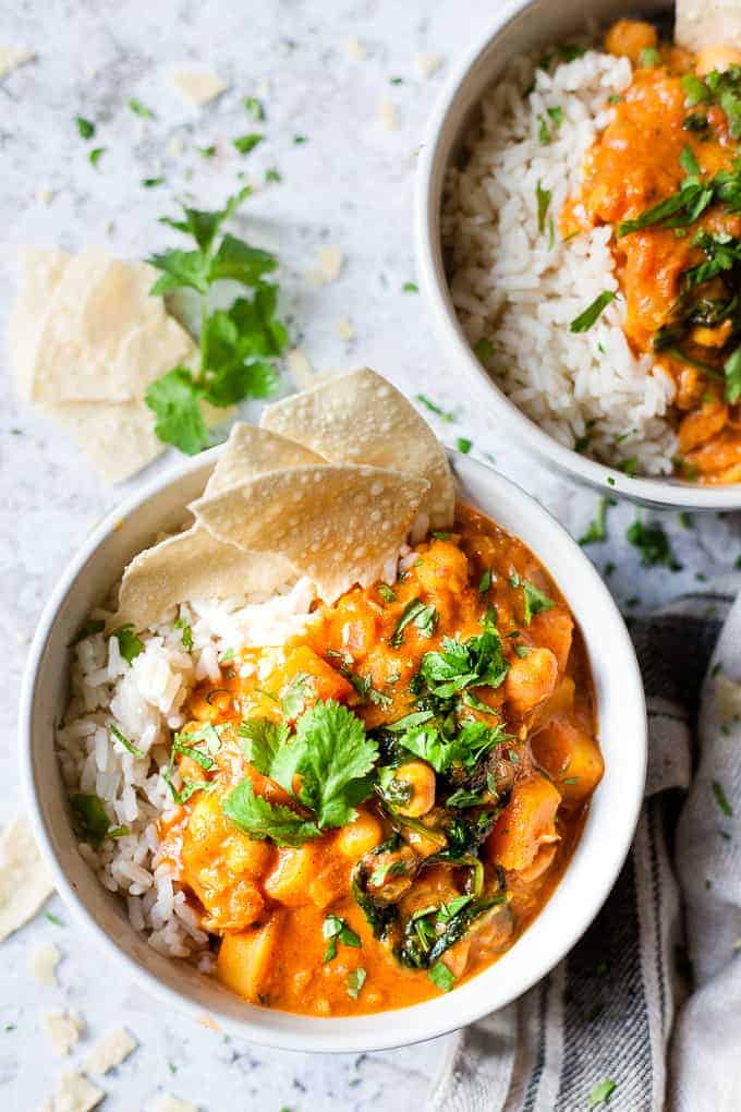 Butternut squash chickpea curry in a white bowl with popadoms.
