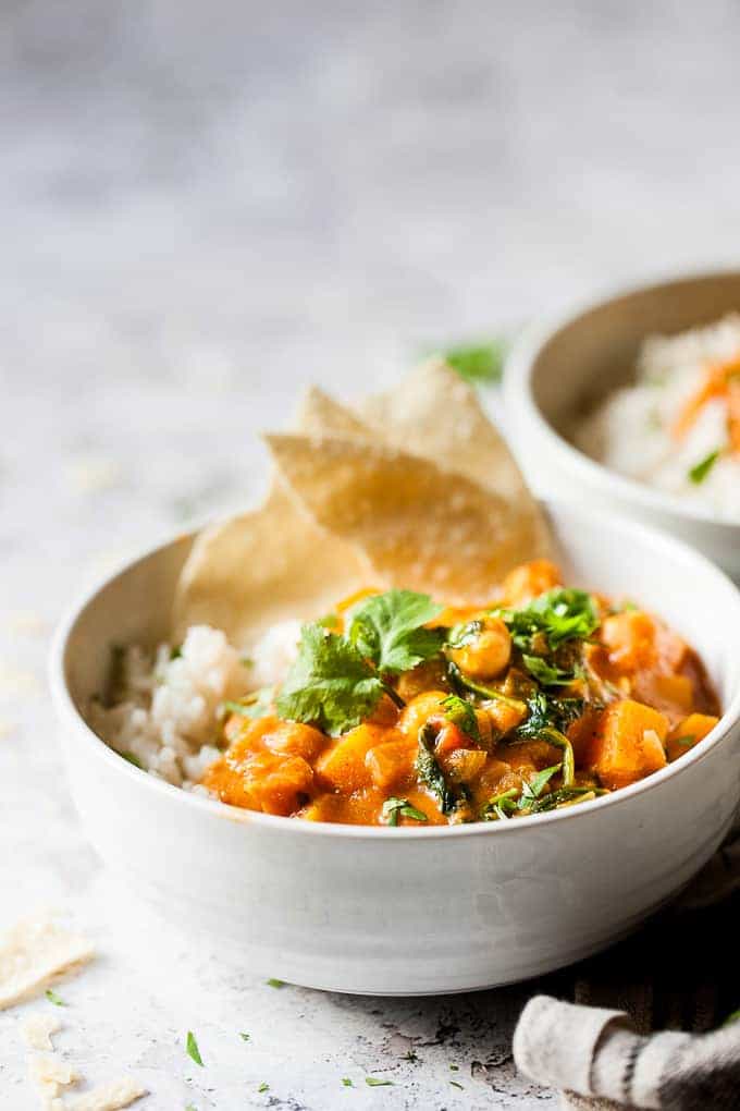 Butternut Squash chickpea curry in white bowls with limes and coriander.