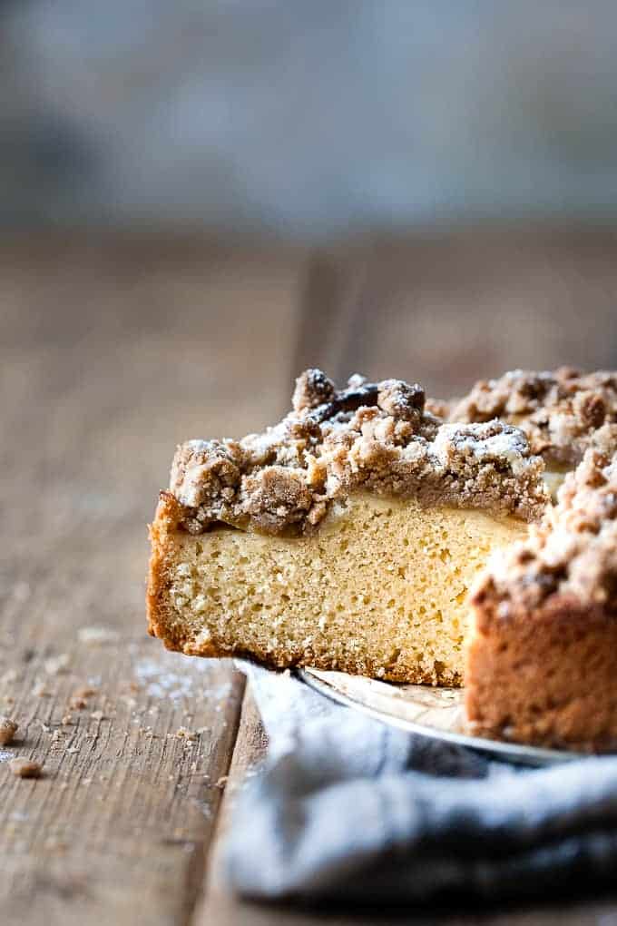 Slice of apple crumb cake on a wooden table.