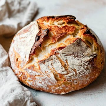 Dutch oven bread on a white table with a baking cloth.