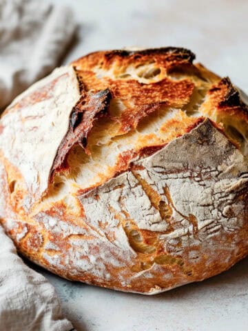 Dutch oven bread on a white table with a baking cloth.