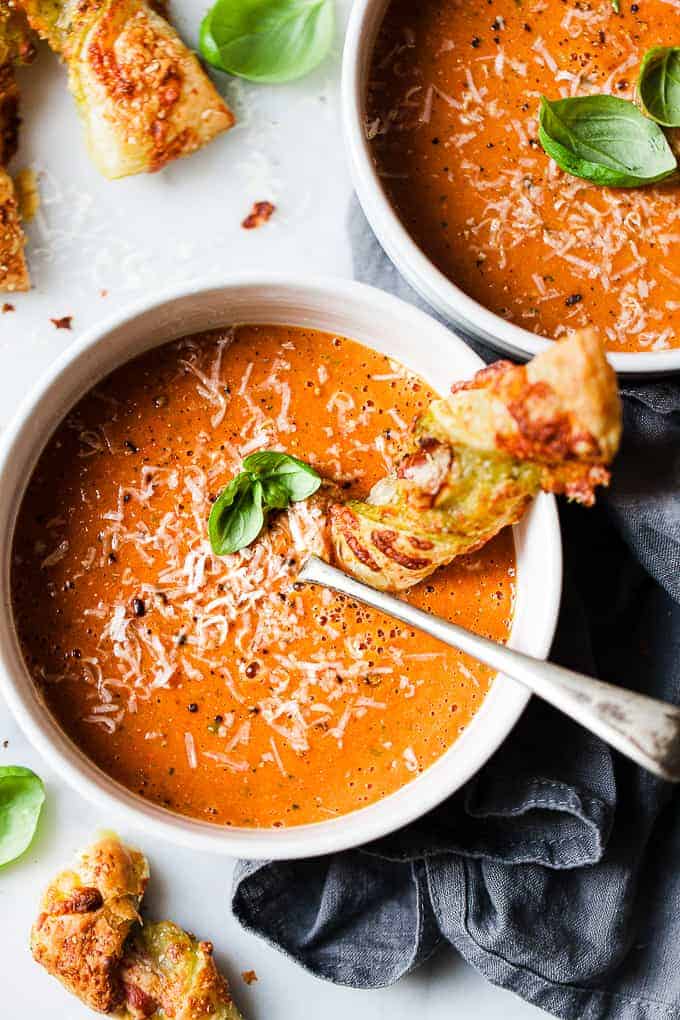 healthy roasted tomato soup in white bowls on a white table.
