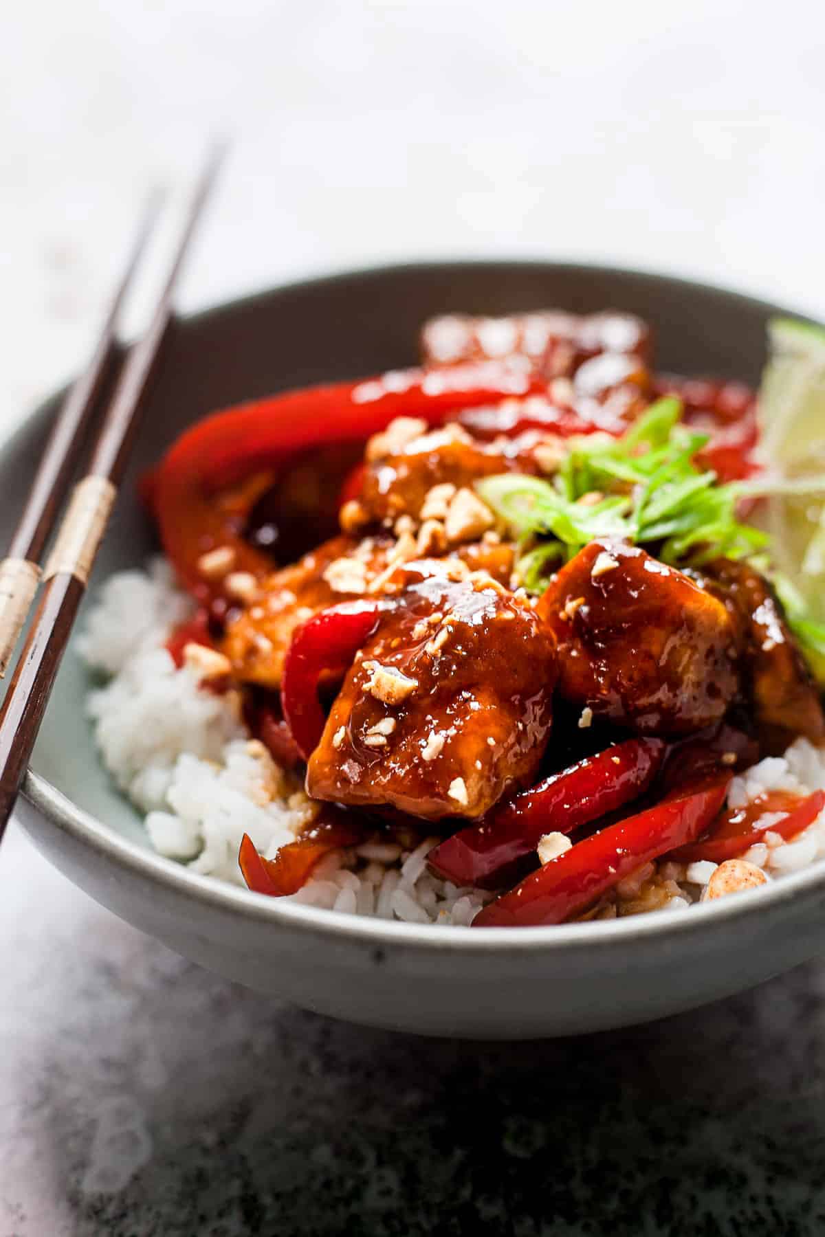 Sticky chicken with peppers and peanuts in a bowl with rice.
