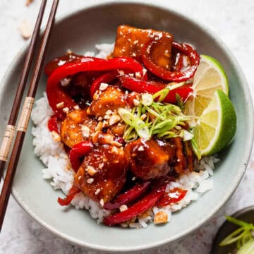 Sticky chicken with peppers and peanuts in a bowl with rice.