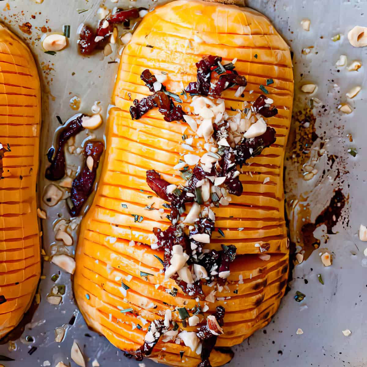 Hasselback butternut squash with bacon and nuts on a baking tray.