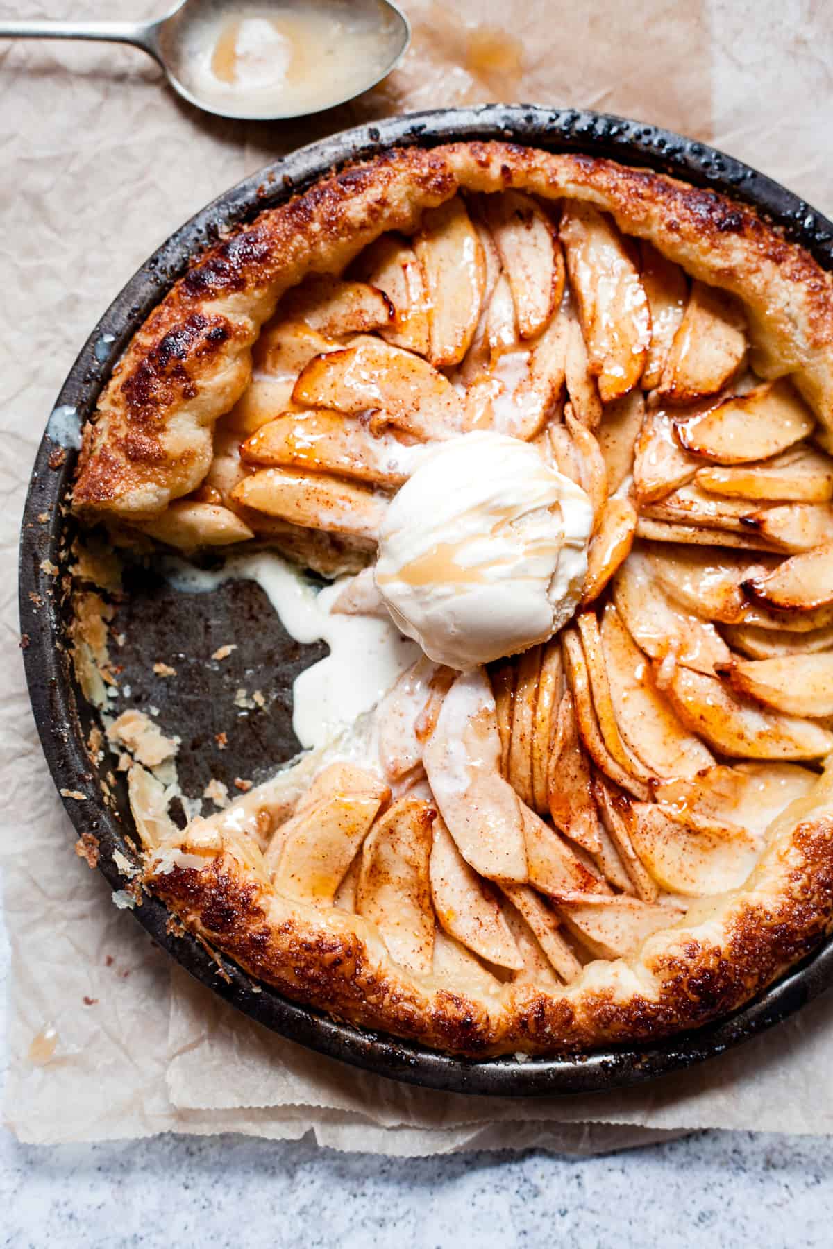 Puff pastry apple tart with a scoop of vanilla ice cream in a pie plate.
