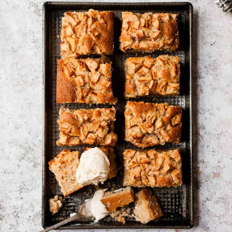 Apple cake in slices on a baking tray with ice cream.