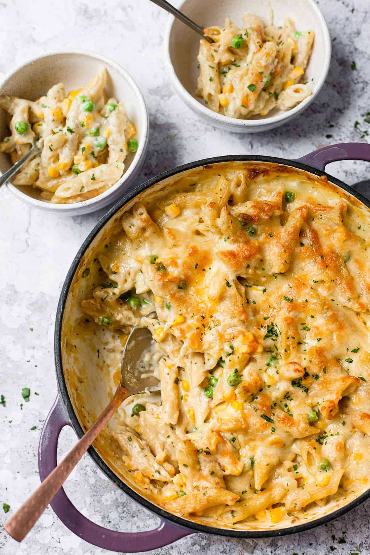 creamy tuna pasta bake with a spoon in it with 2 bowls of pasta