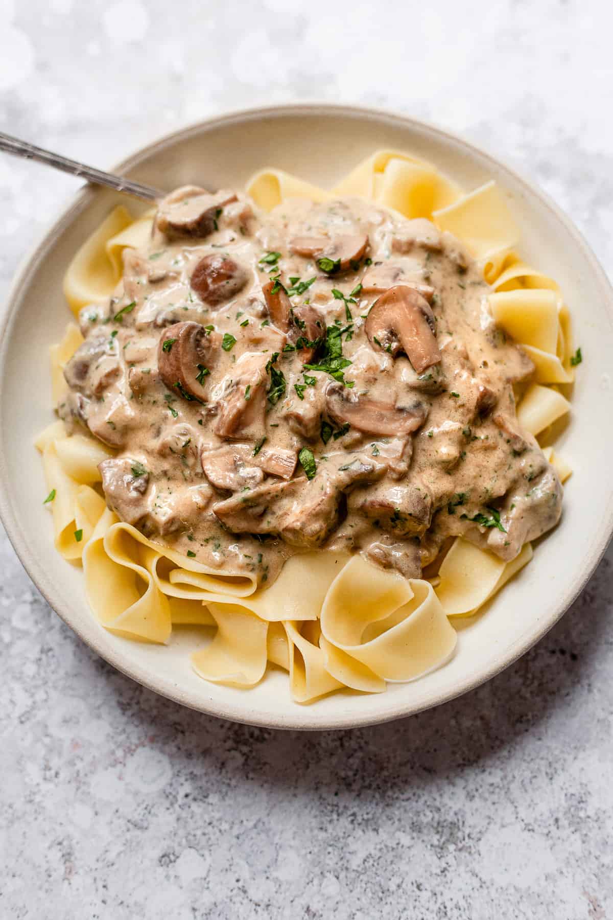 mushroom stroganoff in a white bowl with a fork.