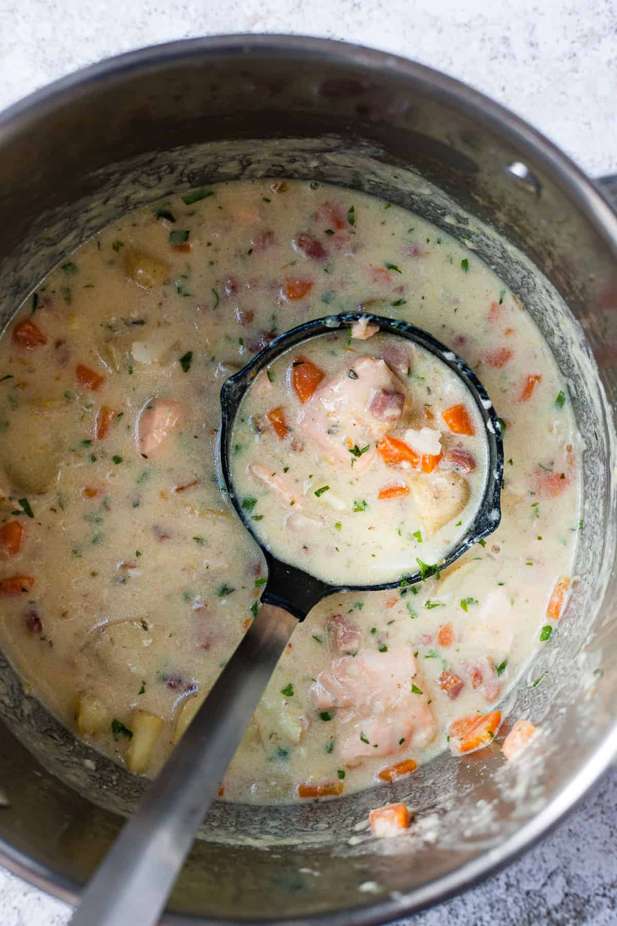 Seafood chowder in a pot with parsley.