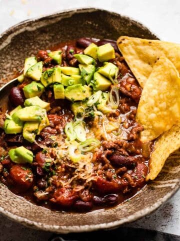slow cooker chilli in a bowl with tortilla chips.