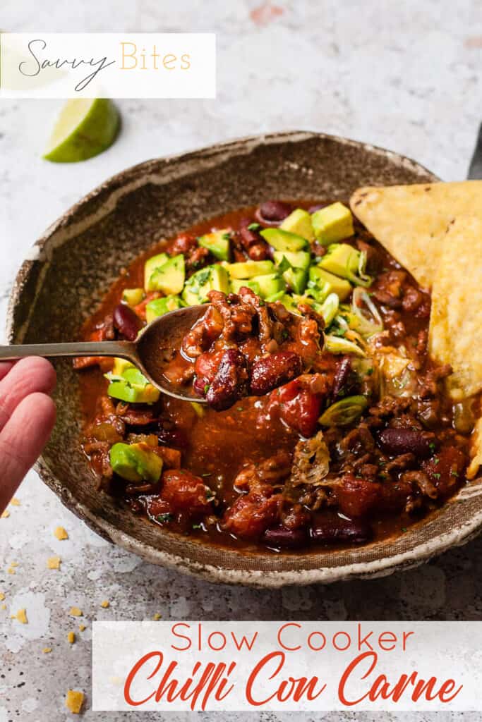 slow cooker chilli in a bowl with tortilla chips. Text overlay.