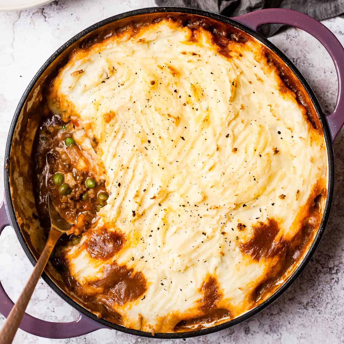 Cottage pie with a spoon in it and a napkin.