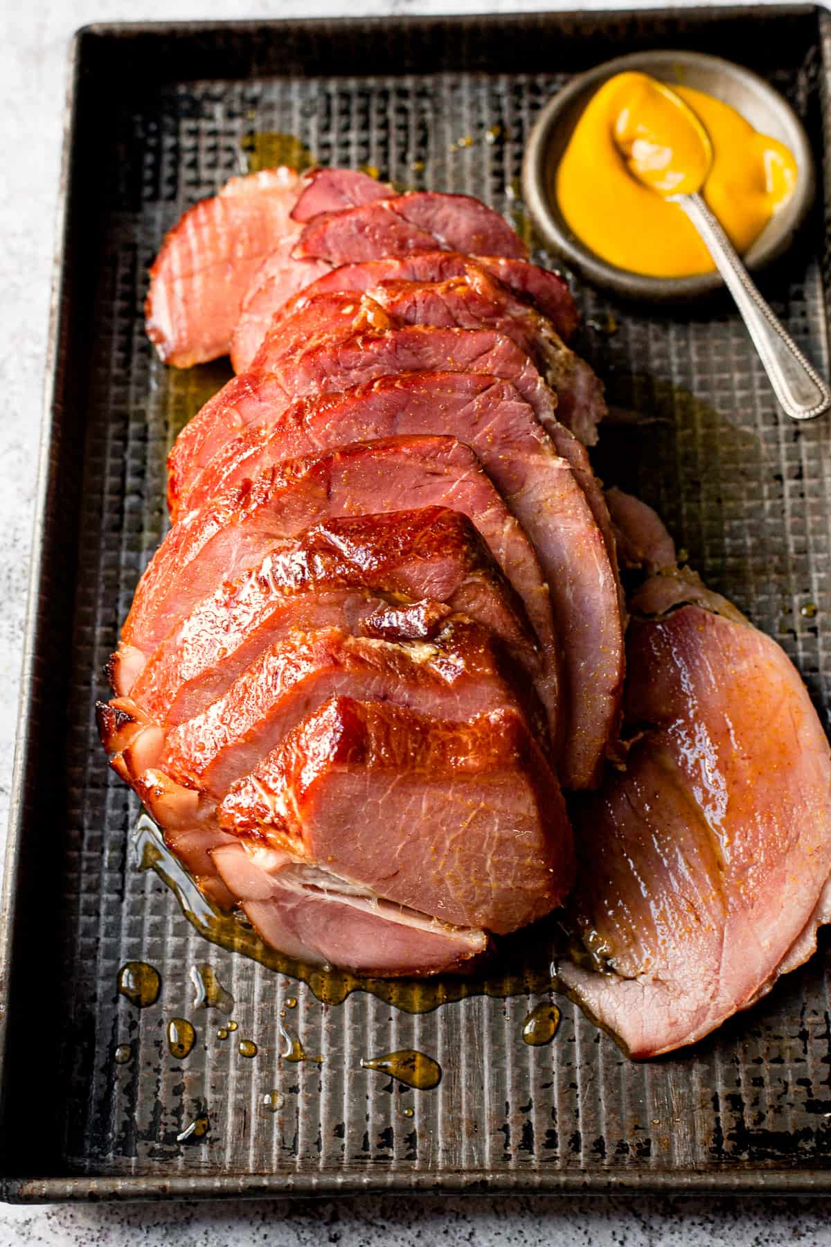 Pieces of Sliced slow cooker gammon that's been glazed and served with mustard.