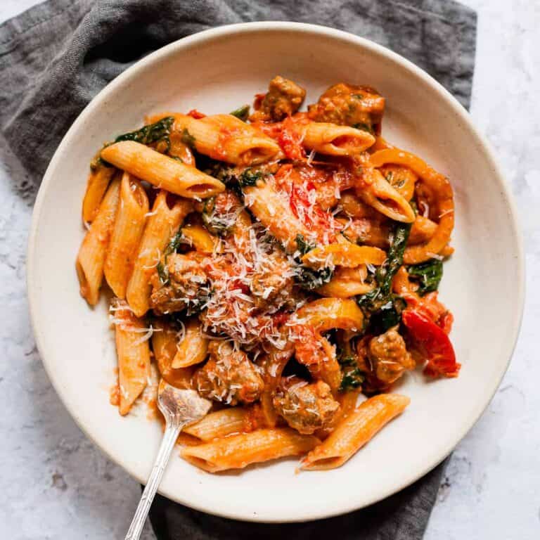 Sausage pasta in a white bowl with a fork.