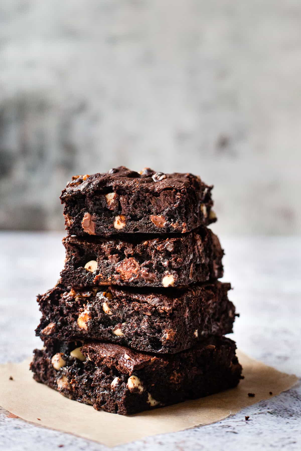 fudgy brownies in a stack on a white table.
