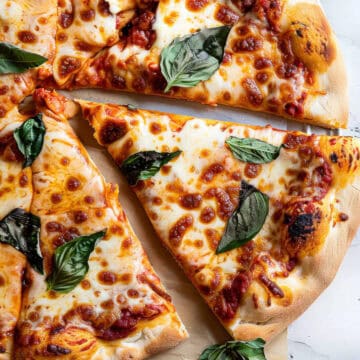 Margherita pizza with basil and mozzarella on a marble table.