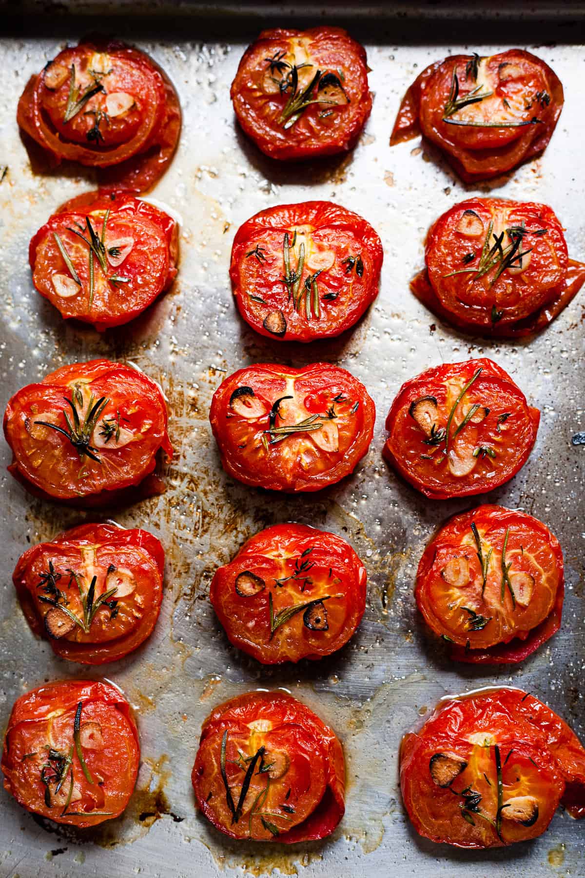 roasted tomatoes on a baking tray with herbs