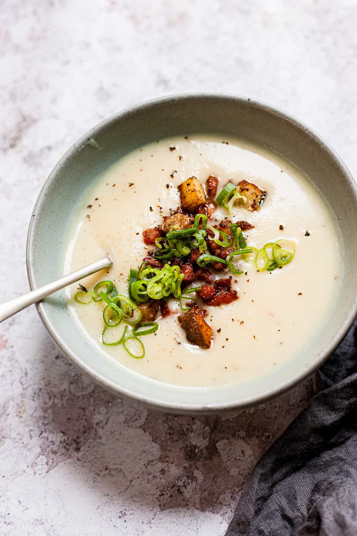 Baked potato soup with bacon bits in a blue bowl.