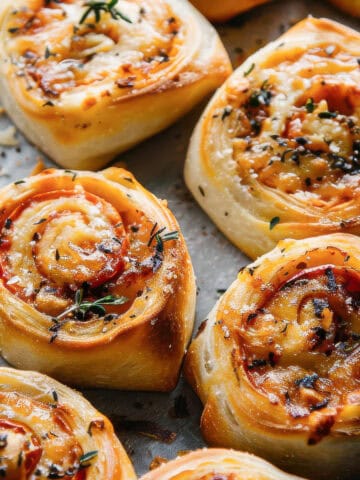 Cheese rolls with herbs on a marble table.