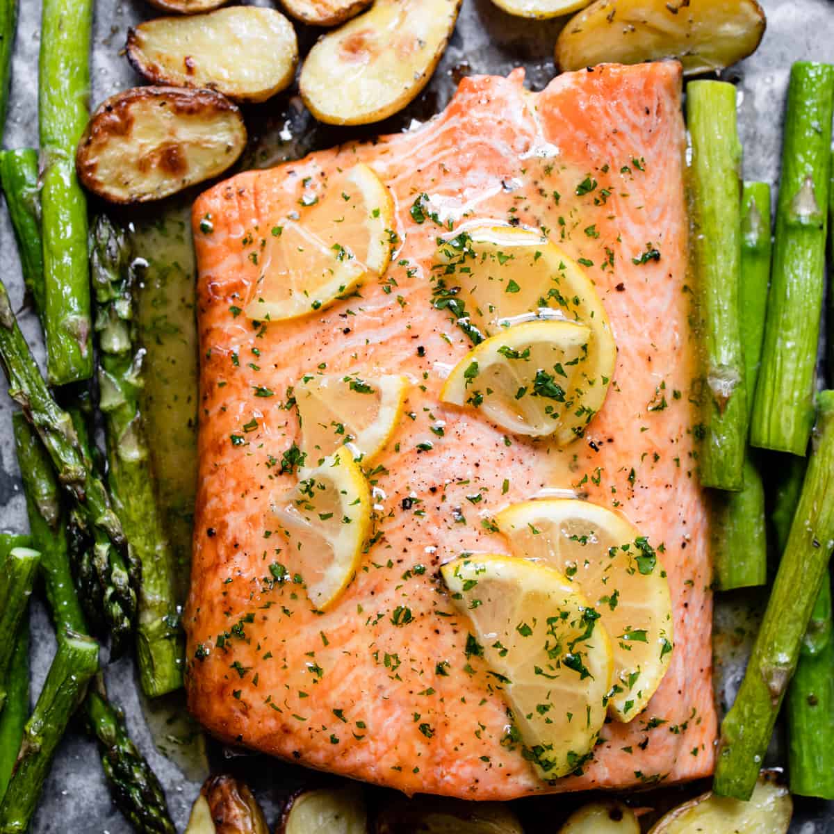 baked salmon with honey garlic butter sauce and lemons on a baking tray