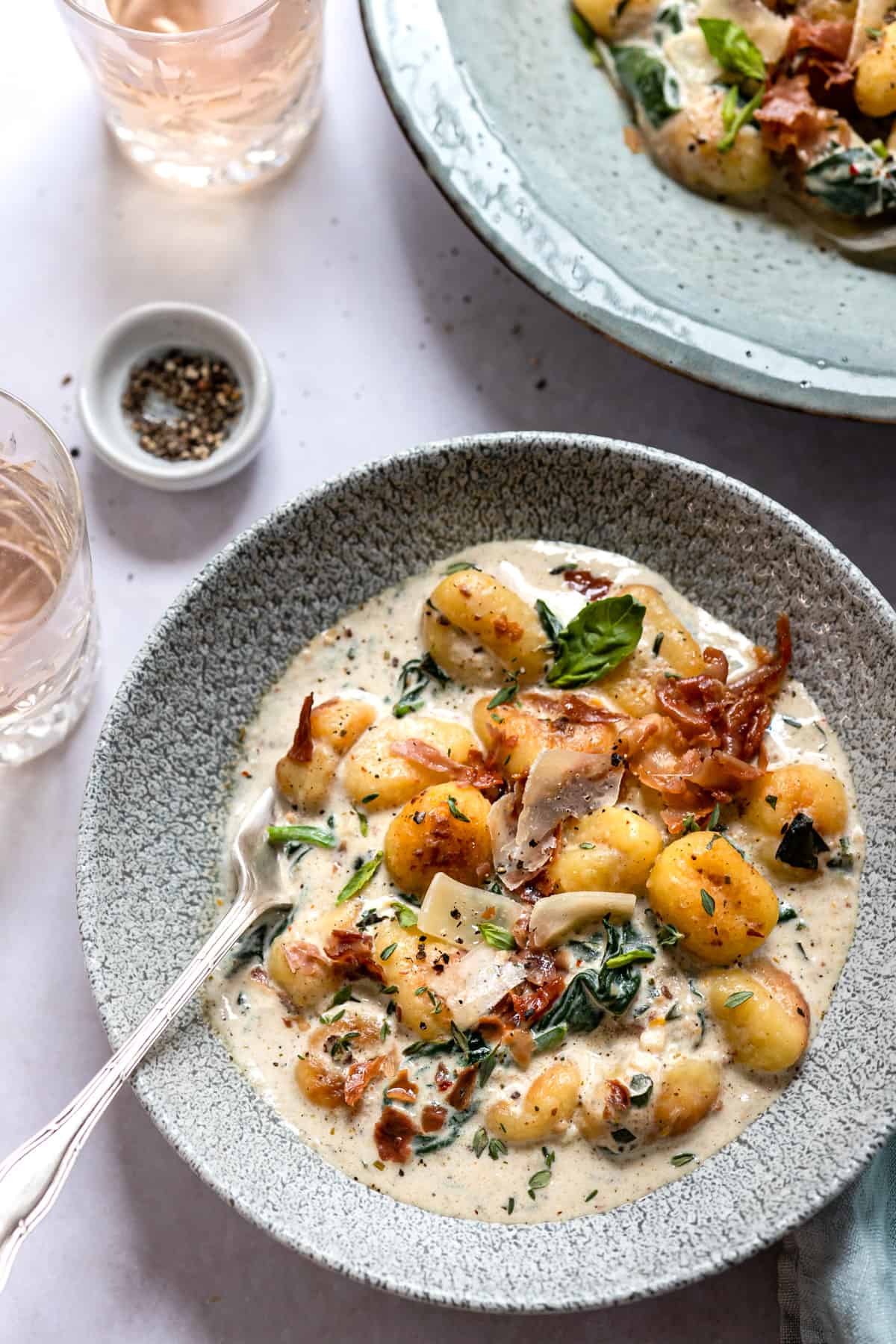 creamy spinach gnocchi in a bowl on a white table