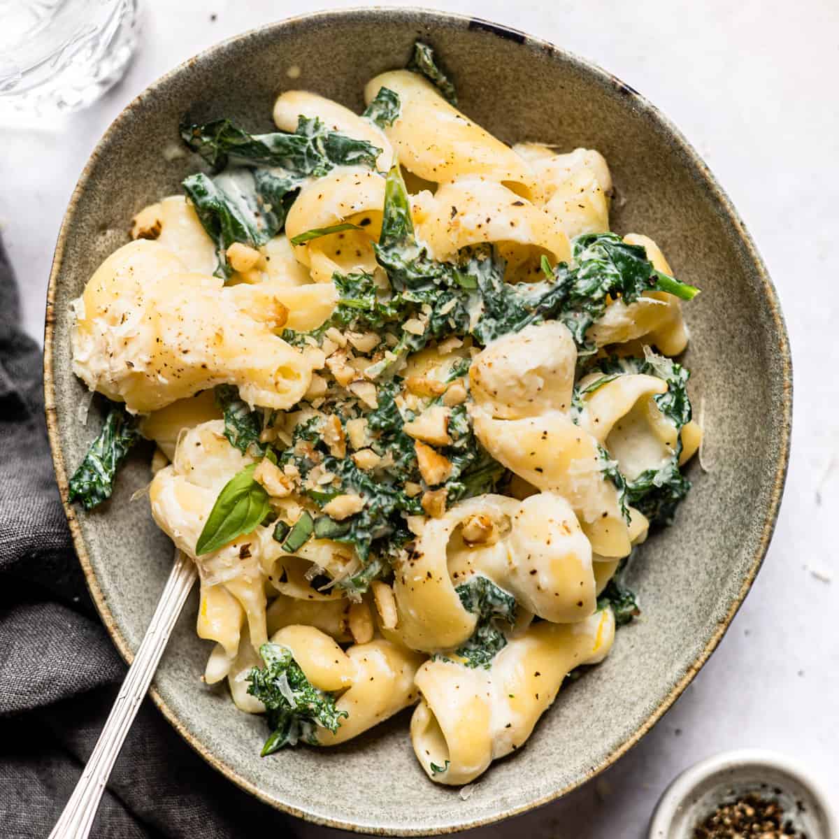 Creamy kale pasta in a grey bowl with pepper