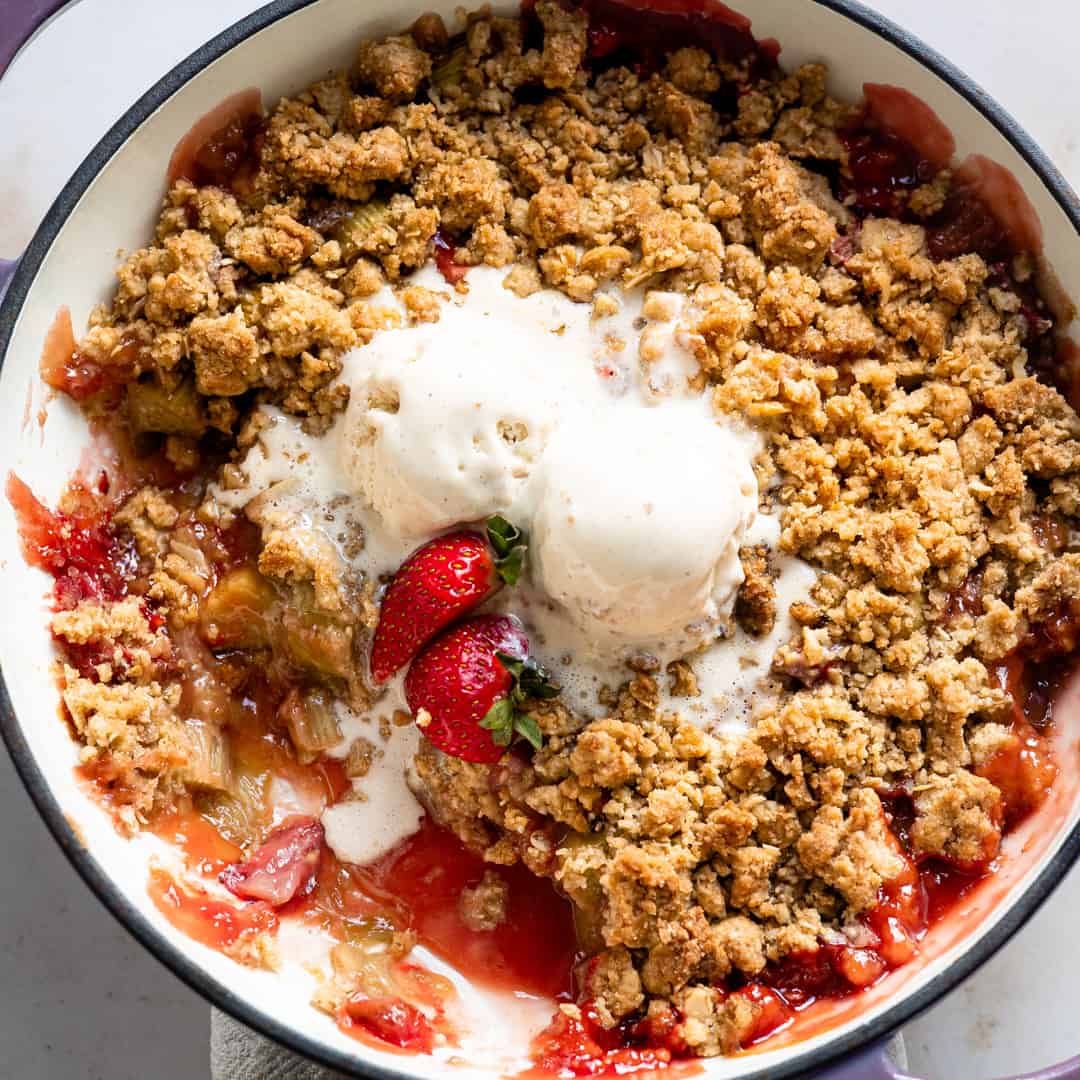 Strawberry Rhubarb crumble in a baking pan with vanilla ice cream.