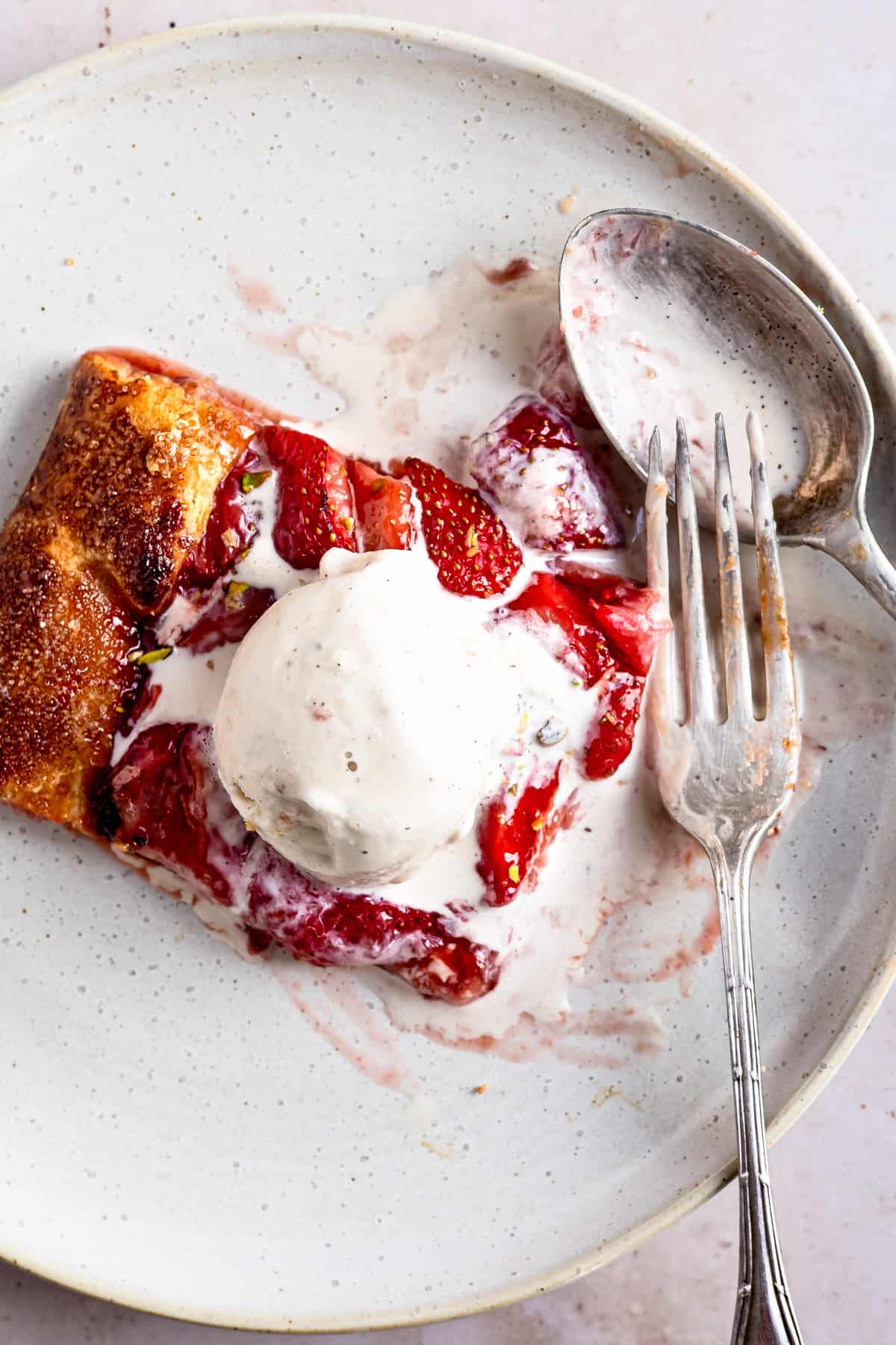 Slice of strawberry tart on a white plate with ice cream. 