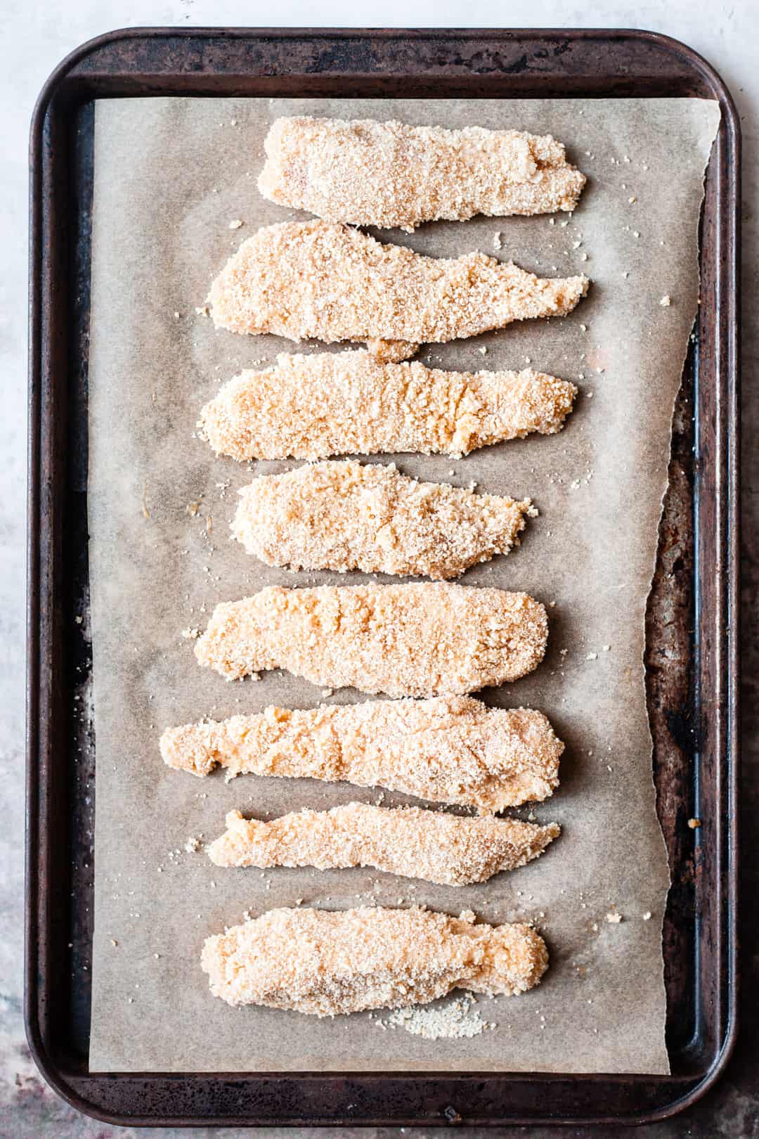 Breaded chicken goujons on a baking tray.