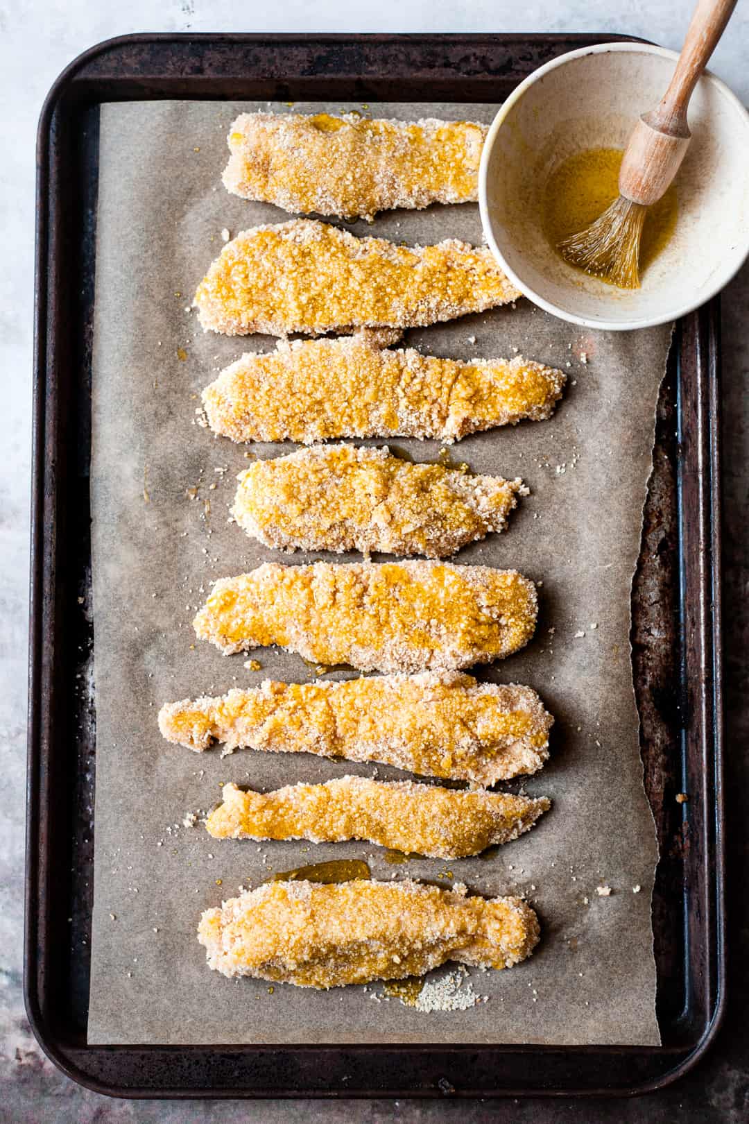 Breaded chicken goujons on a baking tray.