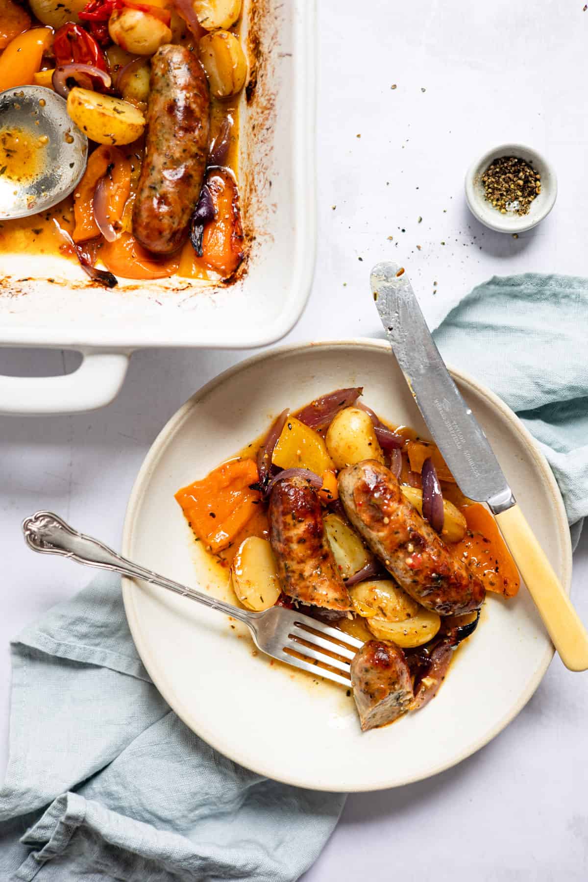 Sausage and potato traybake on a plate with a fork. Aldi recipes