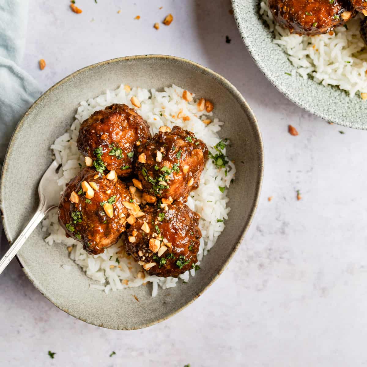 Asian pork meatballs on rice in a white bowl.