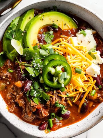 Beef chilli in a bowl with cheese, avocado and coriander.