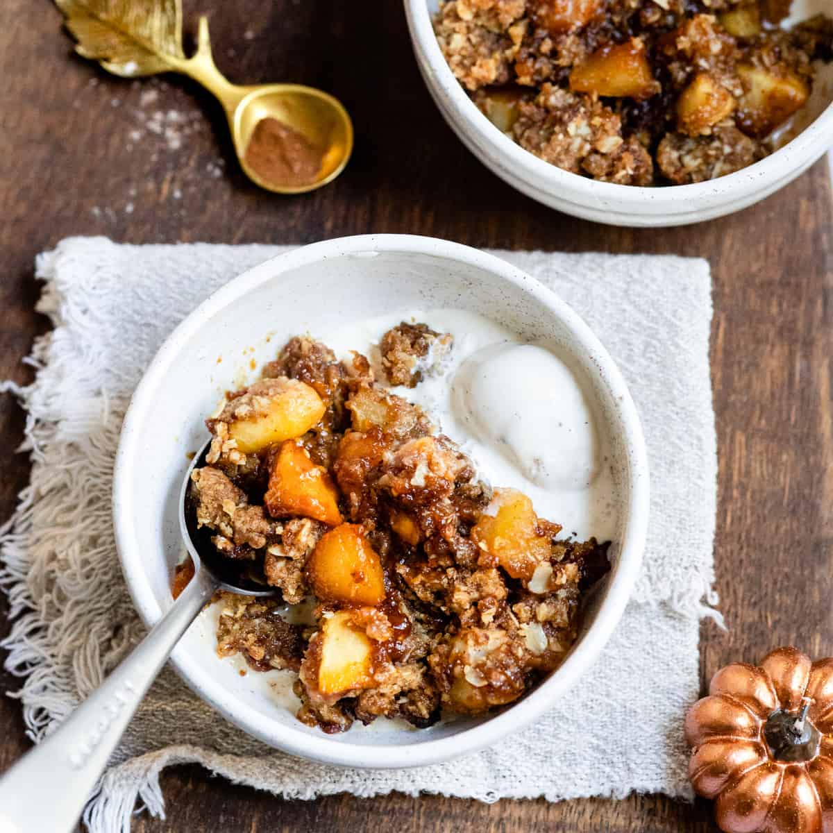 Apple and pear crumble in a white bowl with ice cream