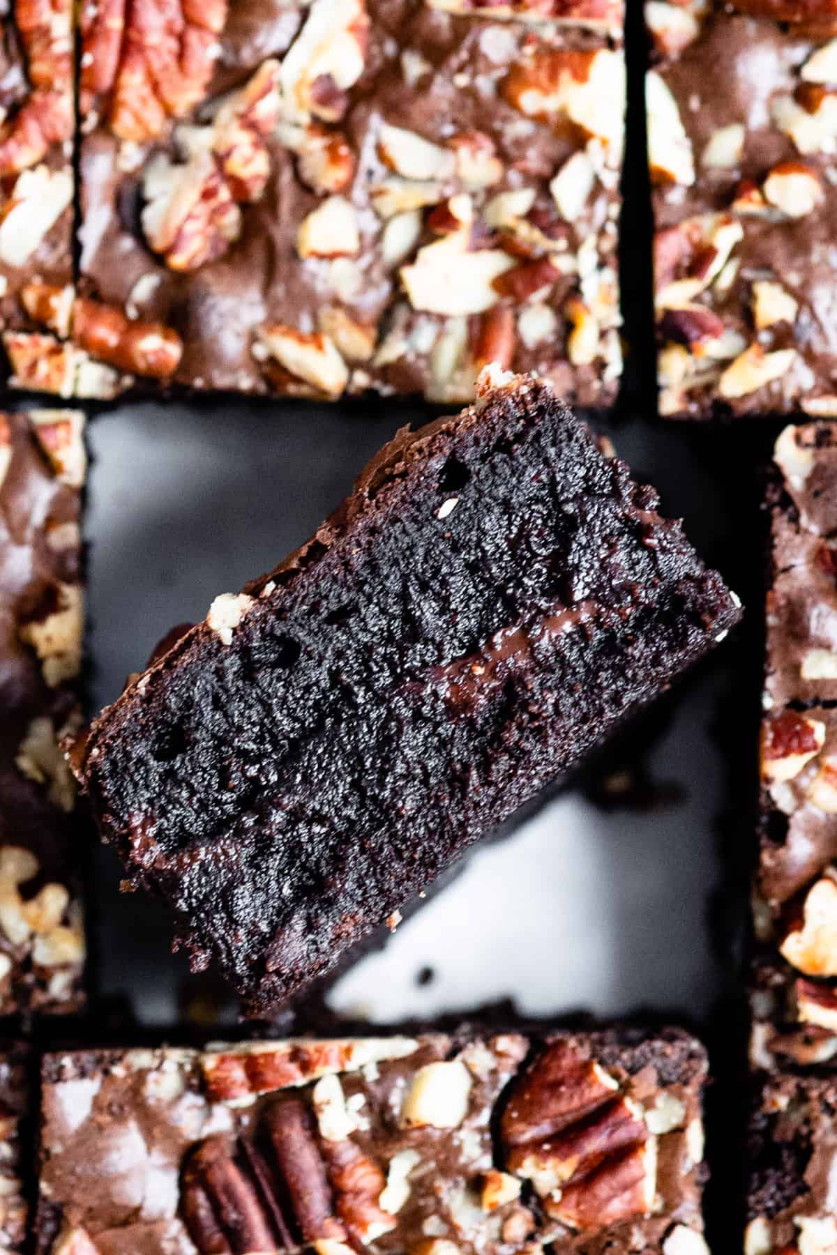 Pecan brownie with pools of chocolate on it's side with other brownies.