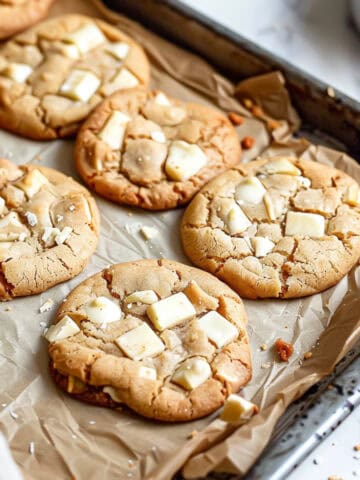 Soft and chewy white chocolate chip cookies on a baking tray.