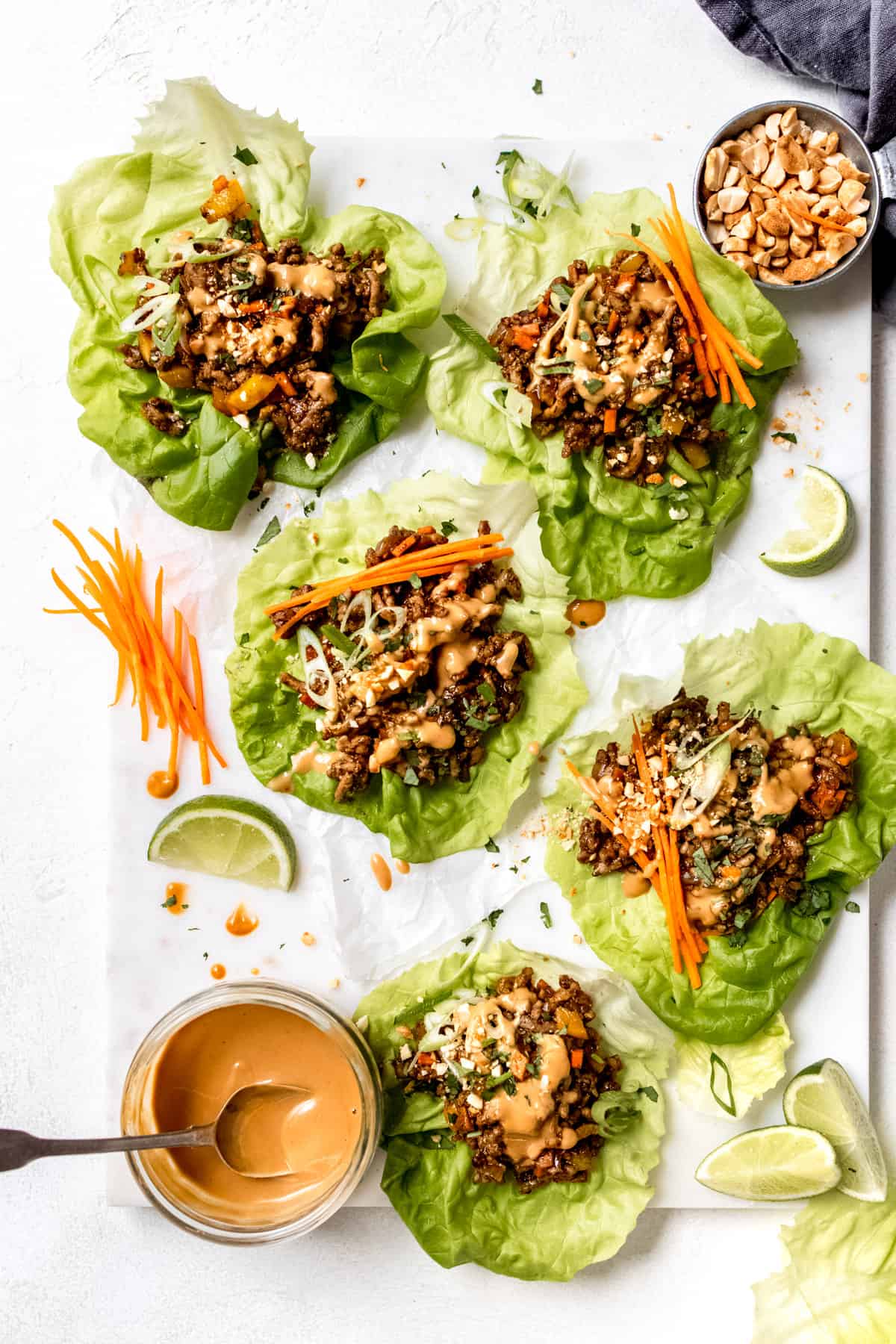 yuk sung - pork mince lettuce wraps on a white table with peanut sauce. 
