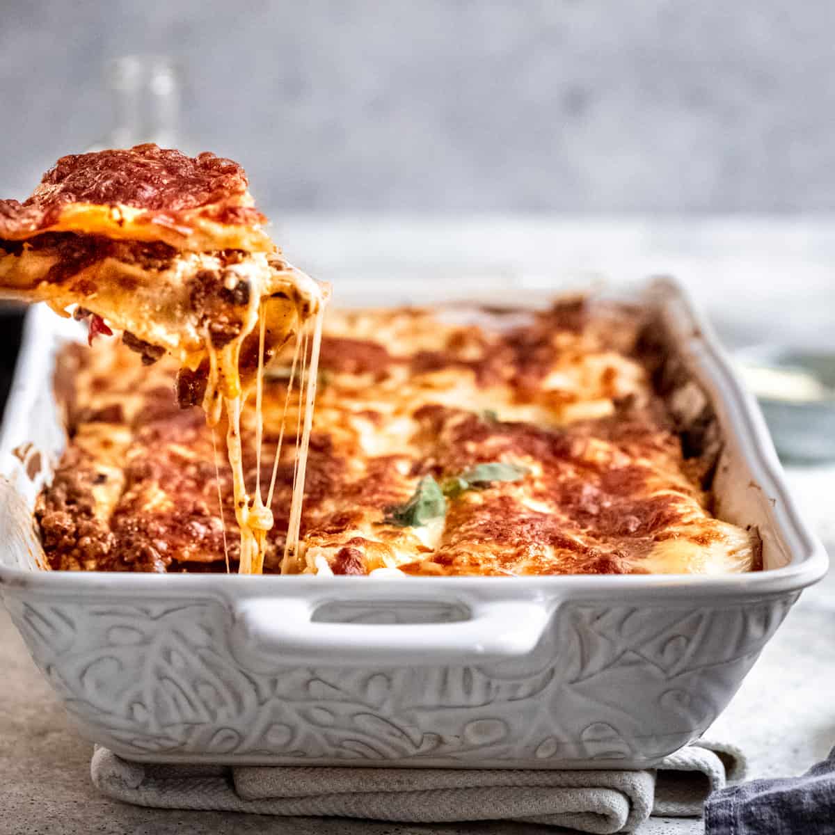 A slice of lasagna being lifted out of a pan.