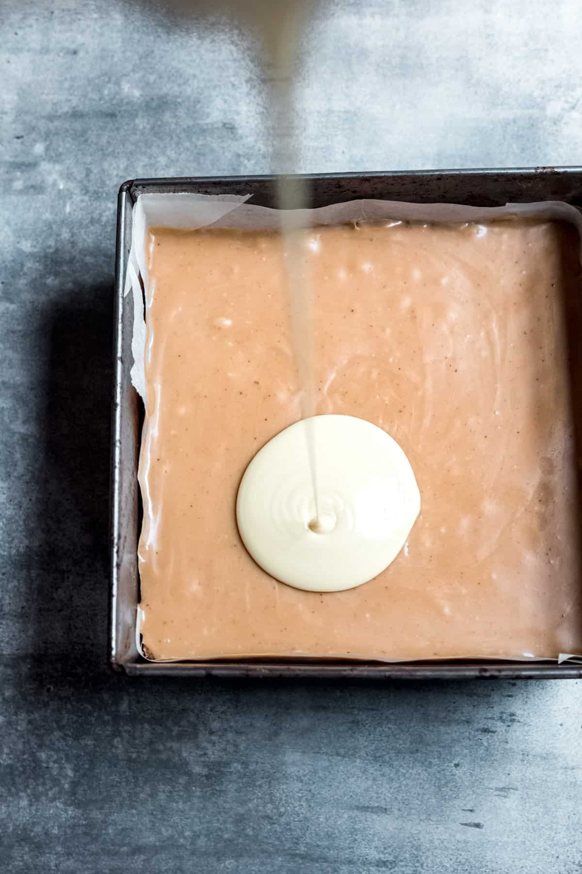 white chocolate being poured over the caramel