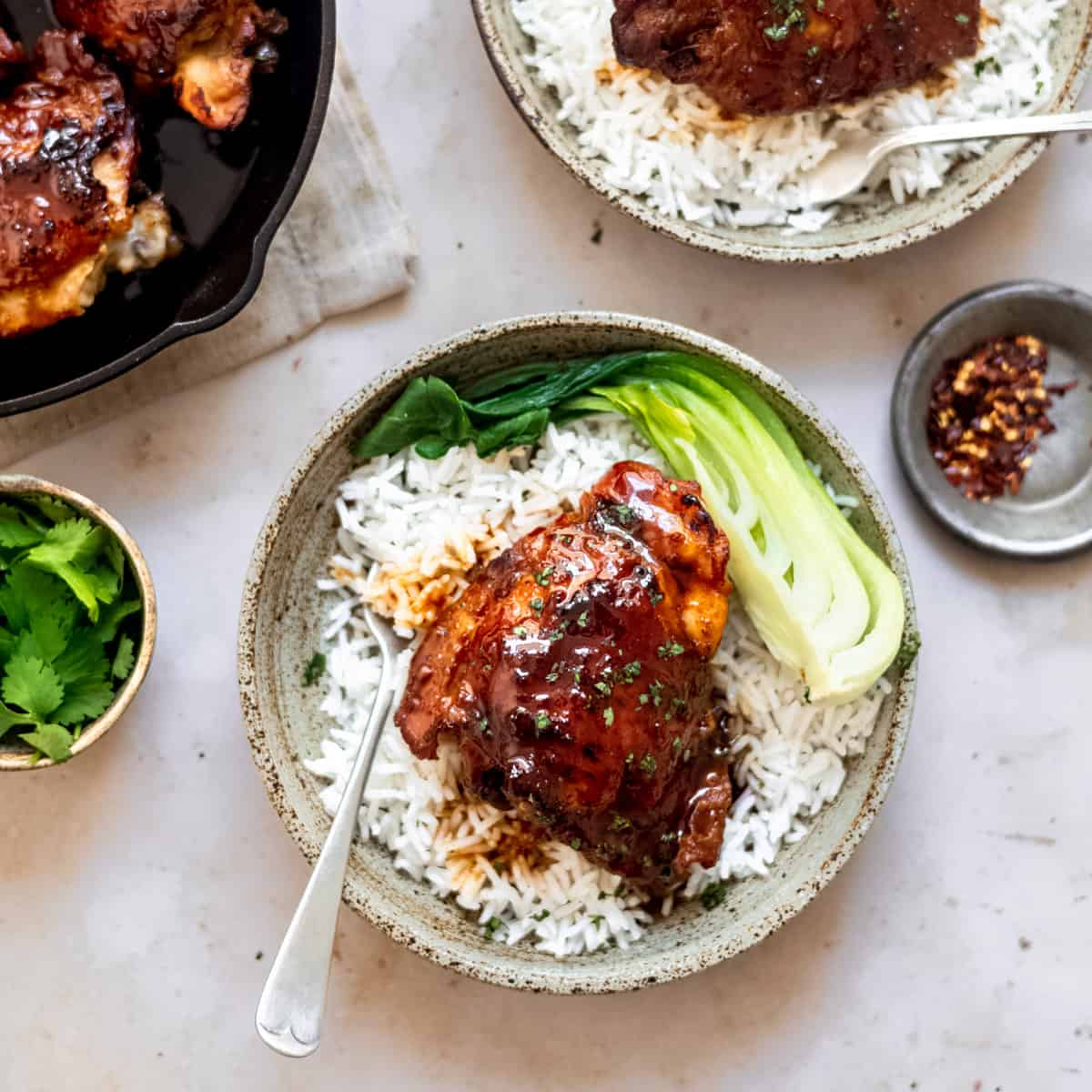 Honey garlic chicken thighs over rice with greens.