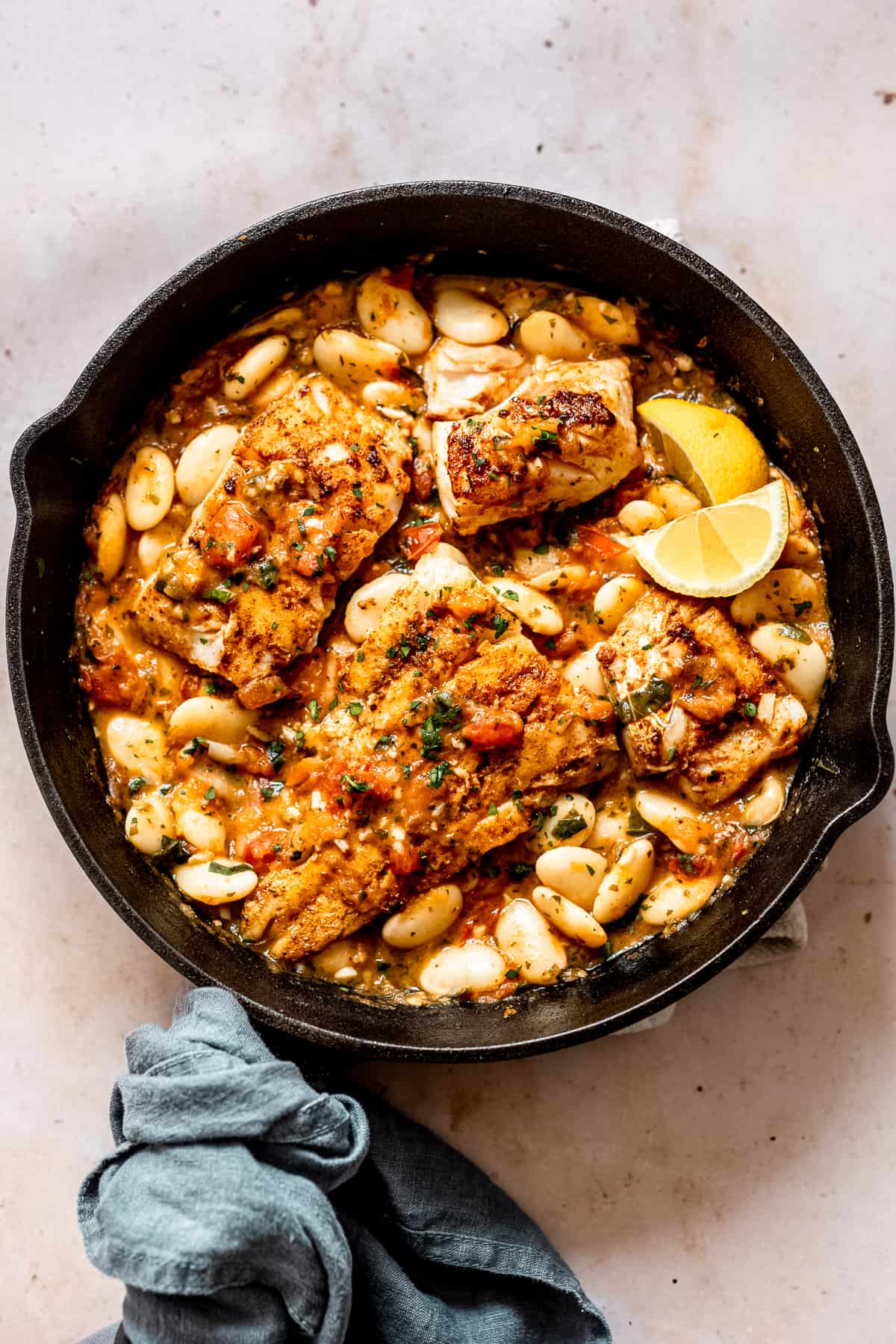 blackened cod in a pan with tomato sauce