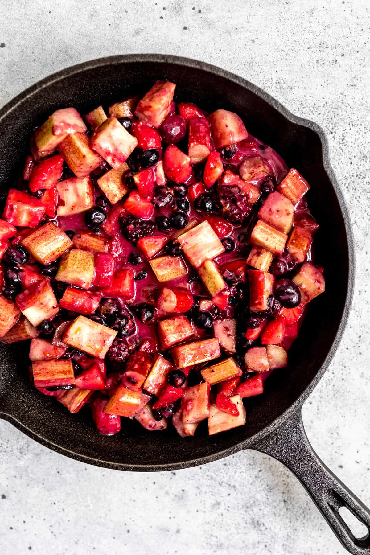 Macerated fruit in a skillet before baking with oat crumble topping.