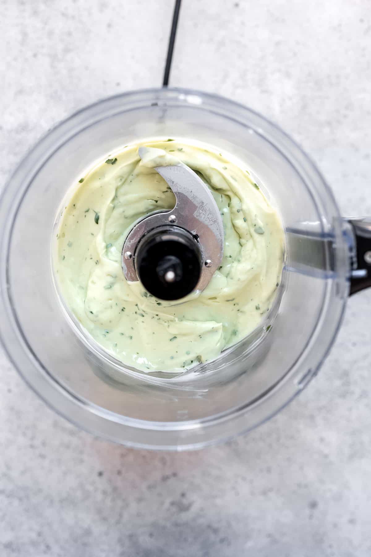 Blended avocado lime crema sauce in the food processor.