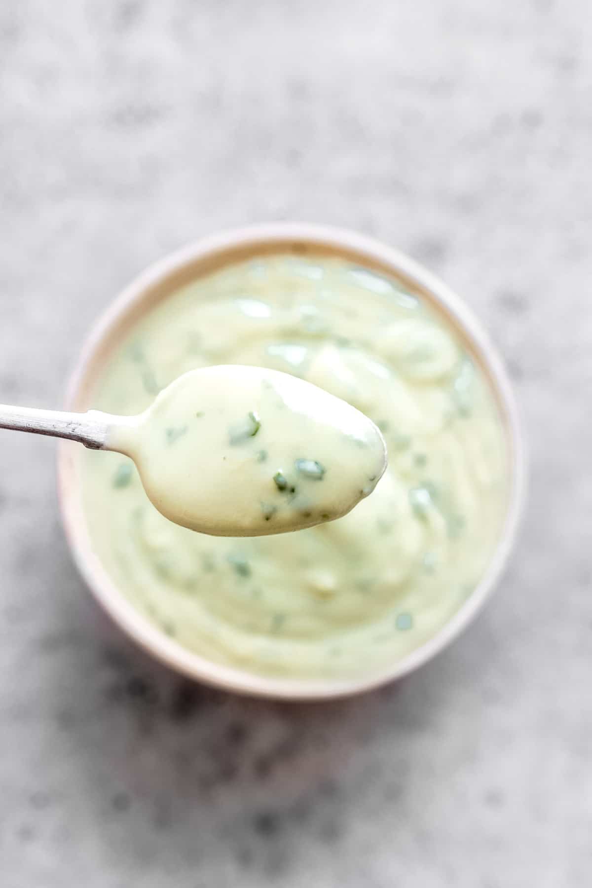 Avocado lime crema blender sauce in a bowl with a spoon.