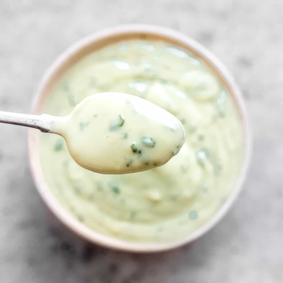 Avocado lime crema in a bowl with a spoon.