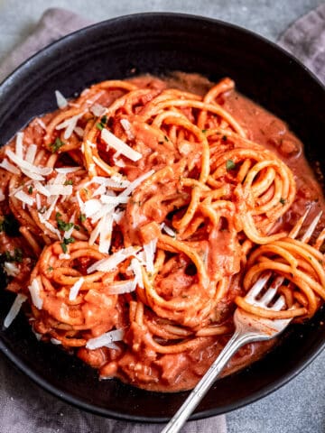 Rose pasta sauce with pasta in a black bowl.