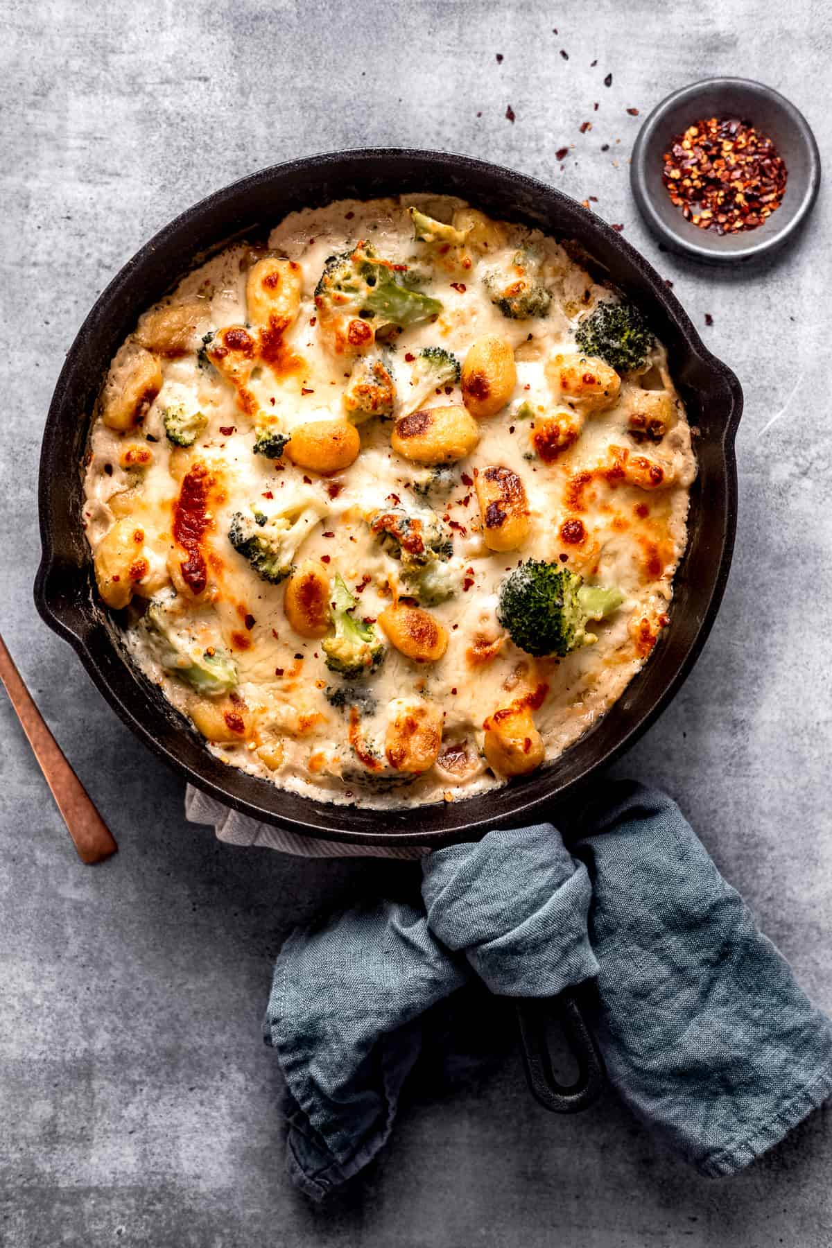 Broccoli gnocchi bake in a skillet with a spoon.