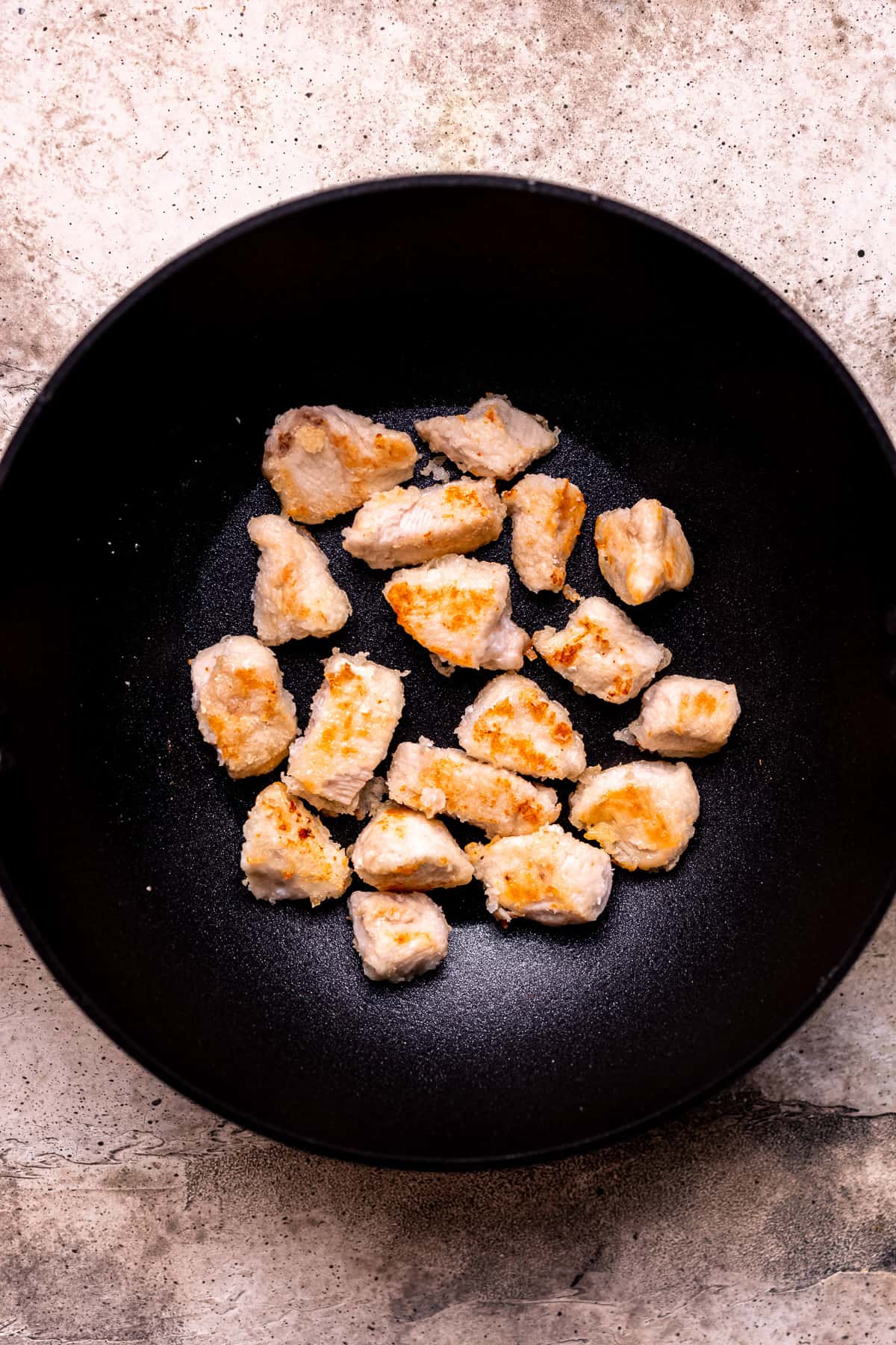 Browning the chicken in a nonstick frying pan.